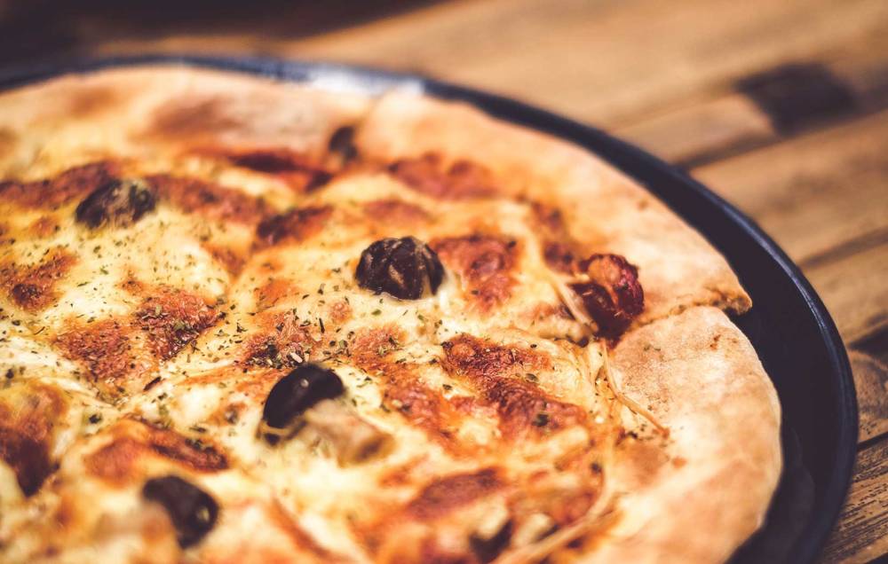 Hauchdünne Pizza mit knusprigem Rand gibt’s bei Pauli Pizza. Unser Tipp: Unbedingt das Knobi-Öl probieren / ©unsplash/Mink Mingle