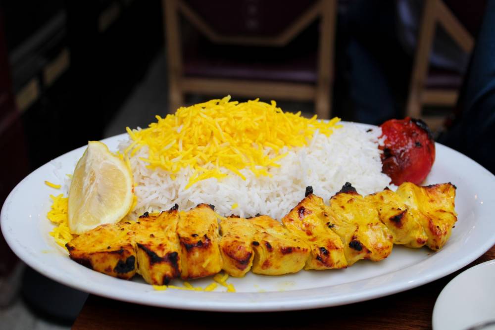 Djudje Kabab mit Safranreis und gegrillten Tomaten ist ein Klassiker der persischen Küche / ©Unsplash
