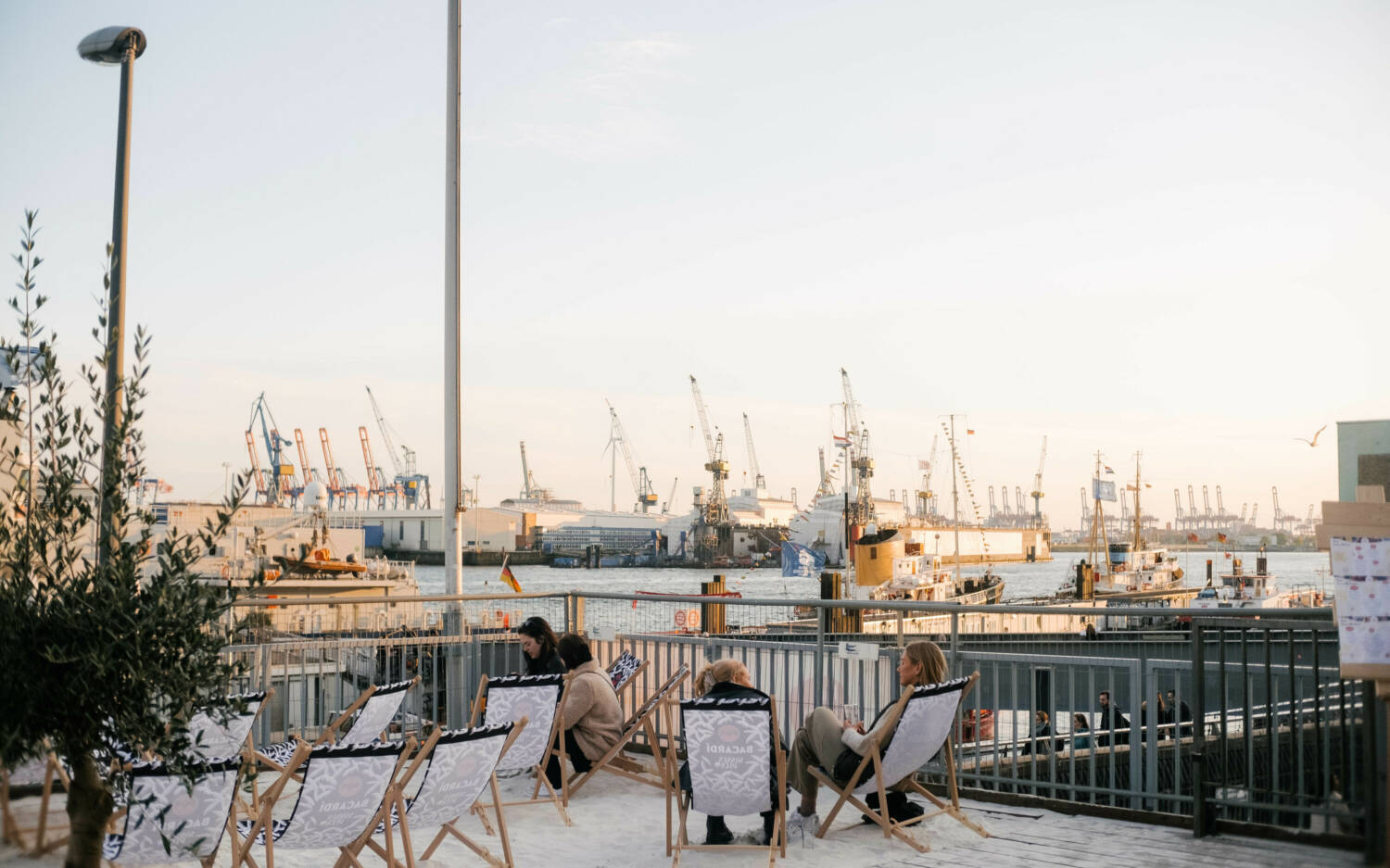 Vom Sonnendeck St. Pauli blickt man auf Wasser, Kräne und untergehende Sonne / ©Lea Harms