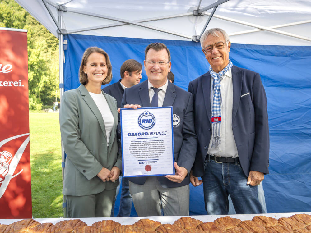 Budnikowsky und Junge Bäckerei feiern Weltrekord mit längstem Franzbrötchen der Welt (v.l.n.r.): Isabelle Junge, Rekordrichter Olaf Kuchenbecker und Cord Wöhlke / ©Budni, Ulrich Schaarschmidt