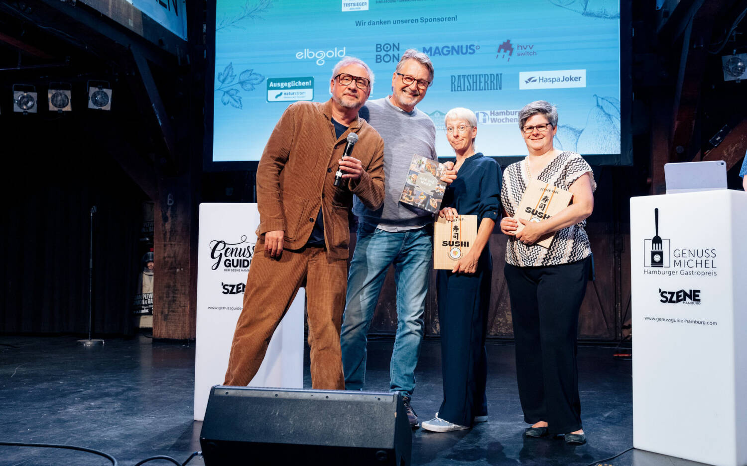 Glückliche Gewinner: Stevan Paul (links) hat auf der Bühne drei seiner Kochbücher verlost / ©Lisa Holiarchuk