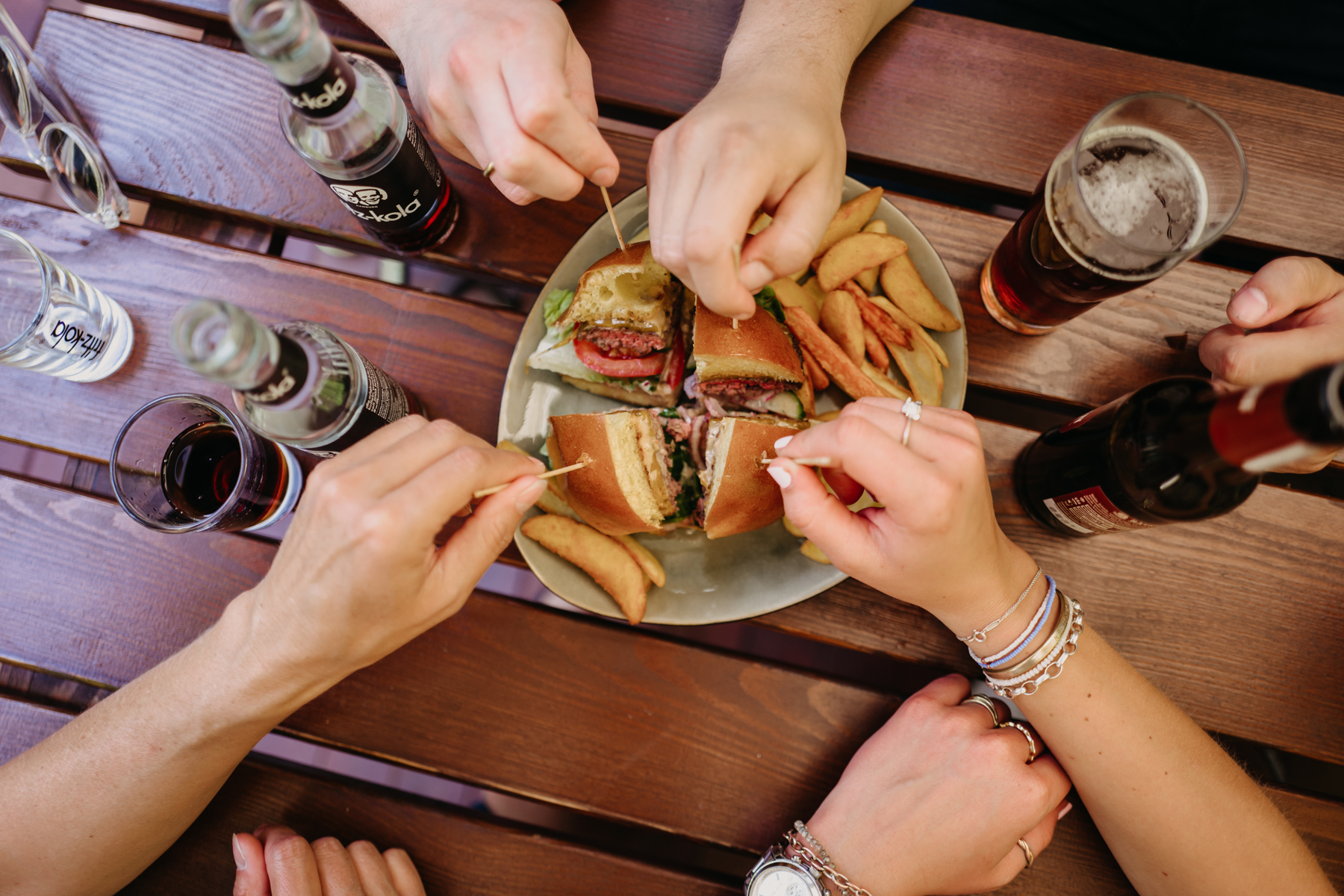 Ein geviertelter Burger wird von 4 Personen geteilt.