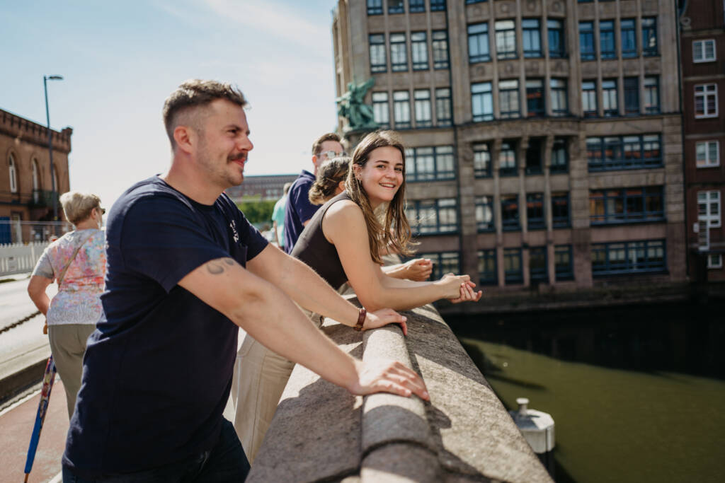 Eine Gruppe junger Leute lehnt am Geländer einer Steinbrücke