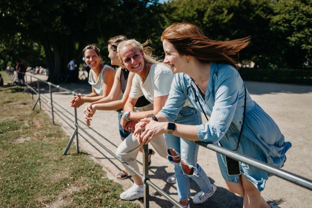 Eine Gruppe Frauen lehnt an einem Geländer im Grünen.