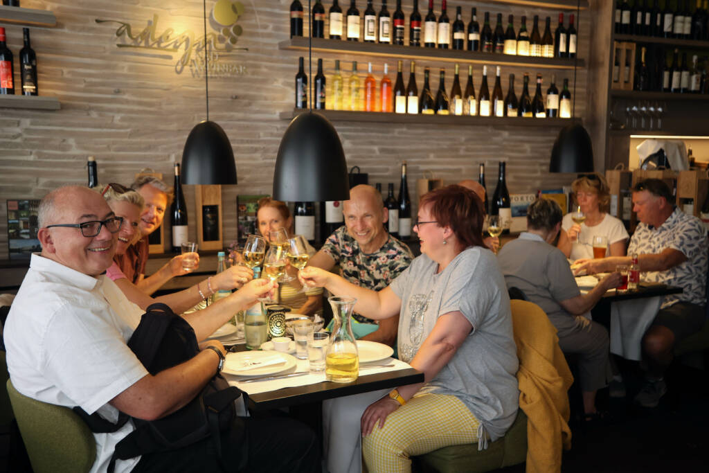 Eine Tischgruppe in einem Restaurant prostet sich zu.