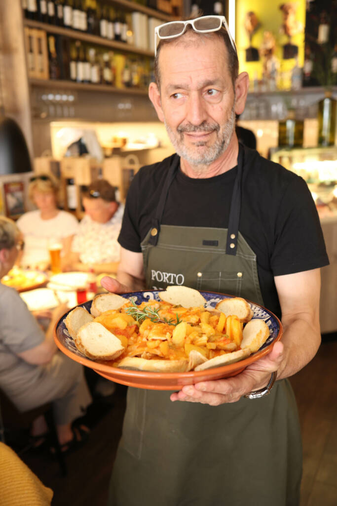 Ein Gastronom bringt eine große Schale gefüllt mit Essen und Brot