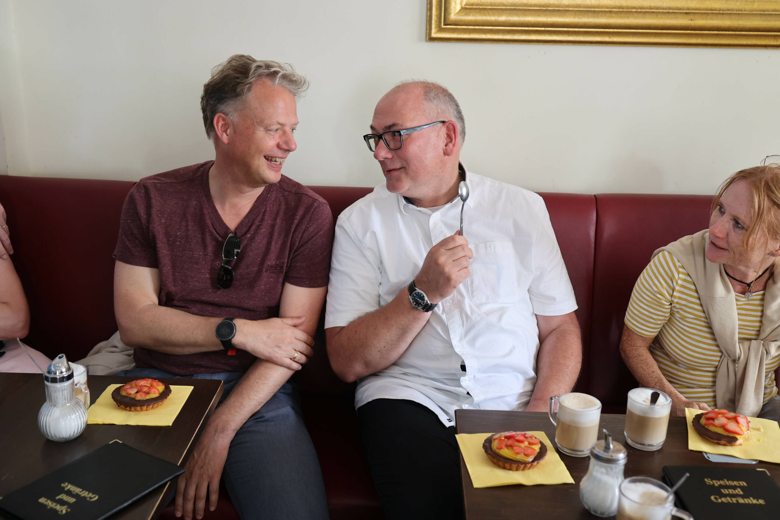 Zwei Herren unterhalten sich bei einem Erdbeertörtchen in einem Cafe