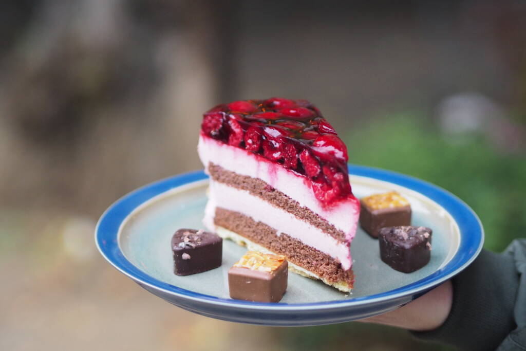 Ein Stück roter Frucht-Torte garniert mit Pralinen.