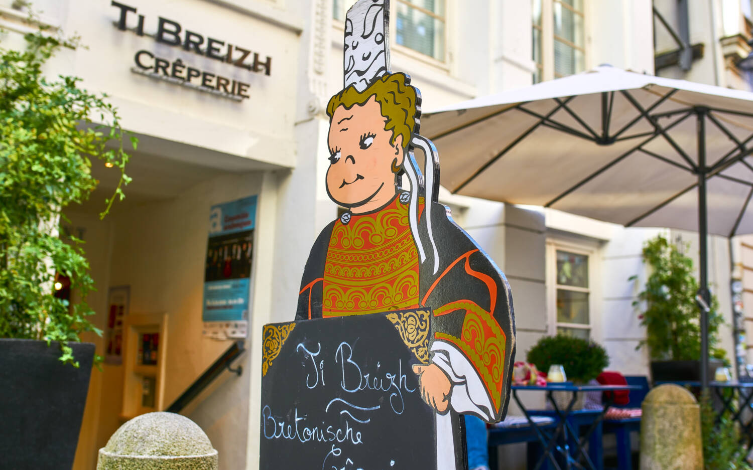 Die Tageskarte der Crêperie wird von einem großen Pappaufsteller gehalten / ©Marc Sill