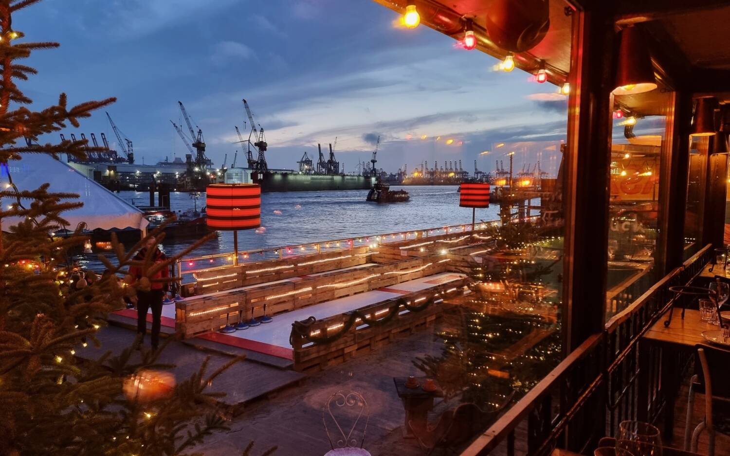 Beleuchtete Tannenbäume und der Blick auf den Hafen: Gemütlich ist es im Winter-Wonderland im Strand Pauli / ©StrandPauli/Lydia Stach
