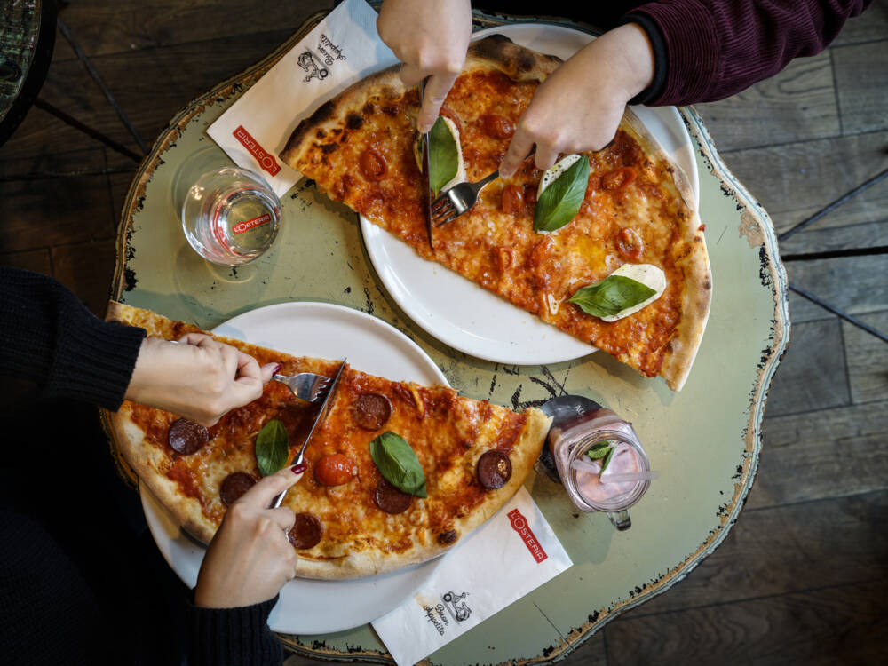 Die L’Osteria ist bekannt für ihre Wagenrad-großen Pizzen, die weit über den Tellerrand hinausragen / ©L’Osteria
