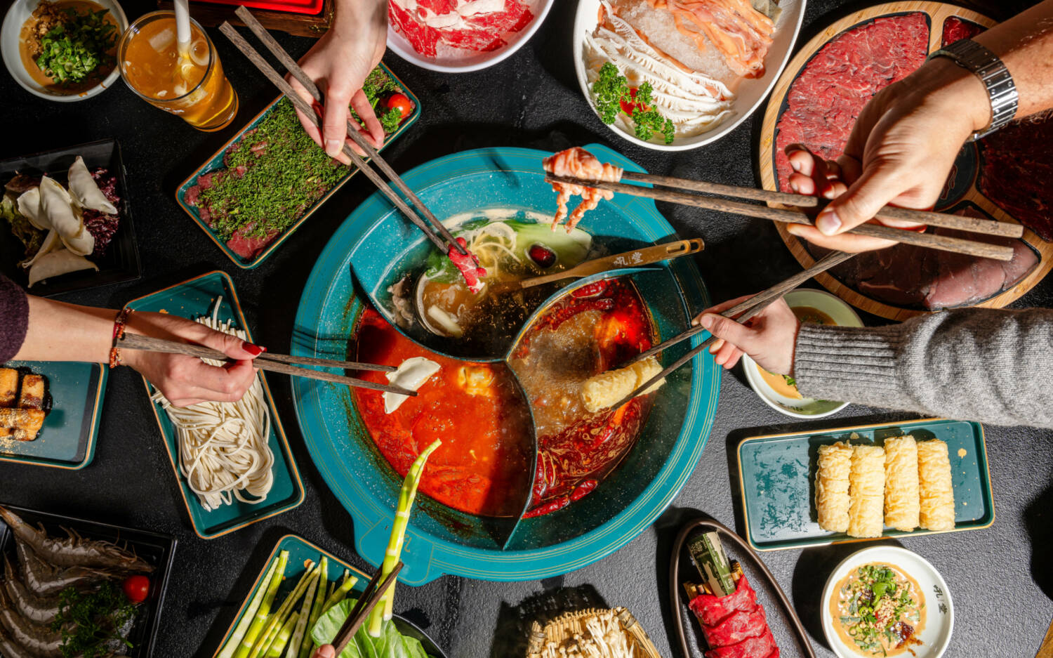 Eine Schüssel in der Mitte, verschiedene Brühen, Gemüse- und Fleischsorten, Dips und Nudeln / ©Houtang Hotpot