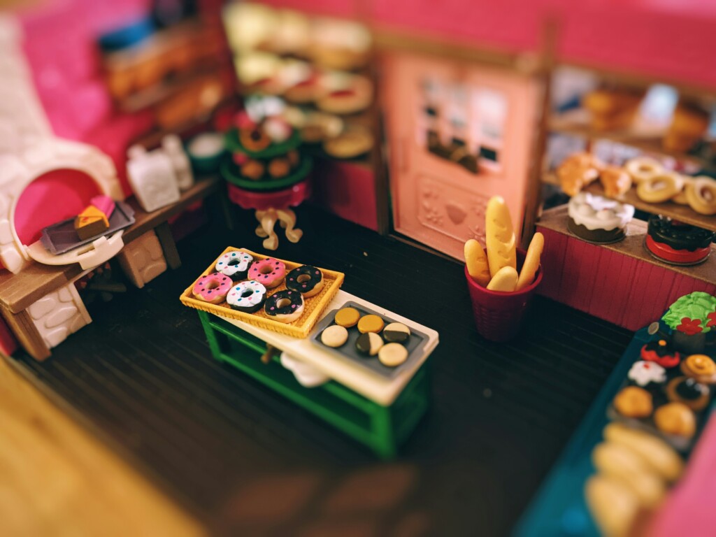 Eine Miniaturküche mit Mini-Donuts und Mini-Keksen auf dem Tisch. Außenrum weiteres Miniatur-Gebäck
