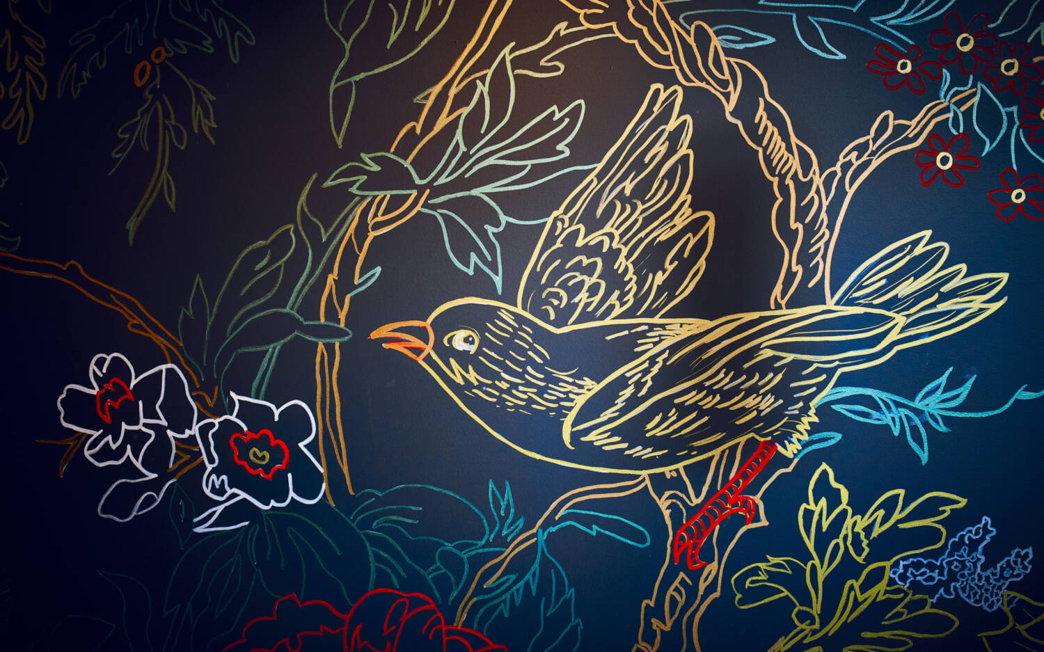 Die dunkel gestrichene Wand ist mit handgemalten Dekorationen versehen. Vögel, Blumen und Blätter finden über den Gästen Platz / ©Marc Sill