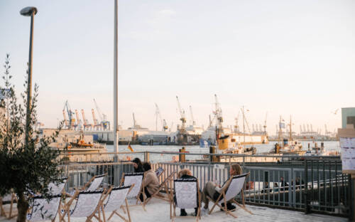 Vom Sonnendeck St. Pauli blickt man auf Wasser, Kräne und untergehende Sonne / ©Lea Harms