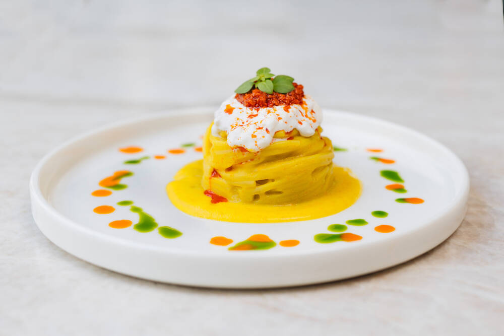 Spätestens jetzt knurrt der Magen: Zwischen grünen und orangenen Farbtupfern aus aromatischen Ölen liegen Spaghetti in einer verführerischen Anrichtungsweise / ©Julia Schumacher