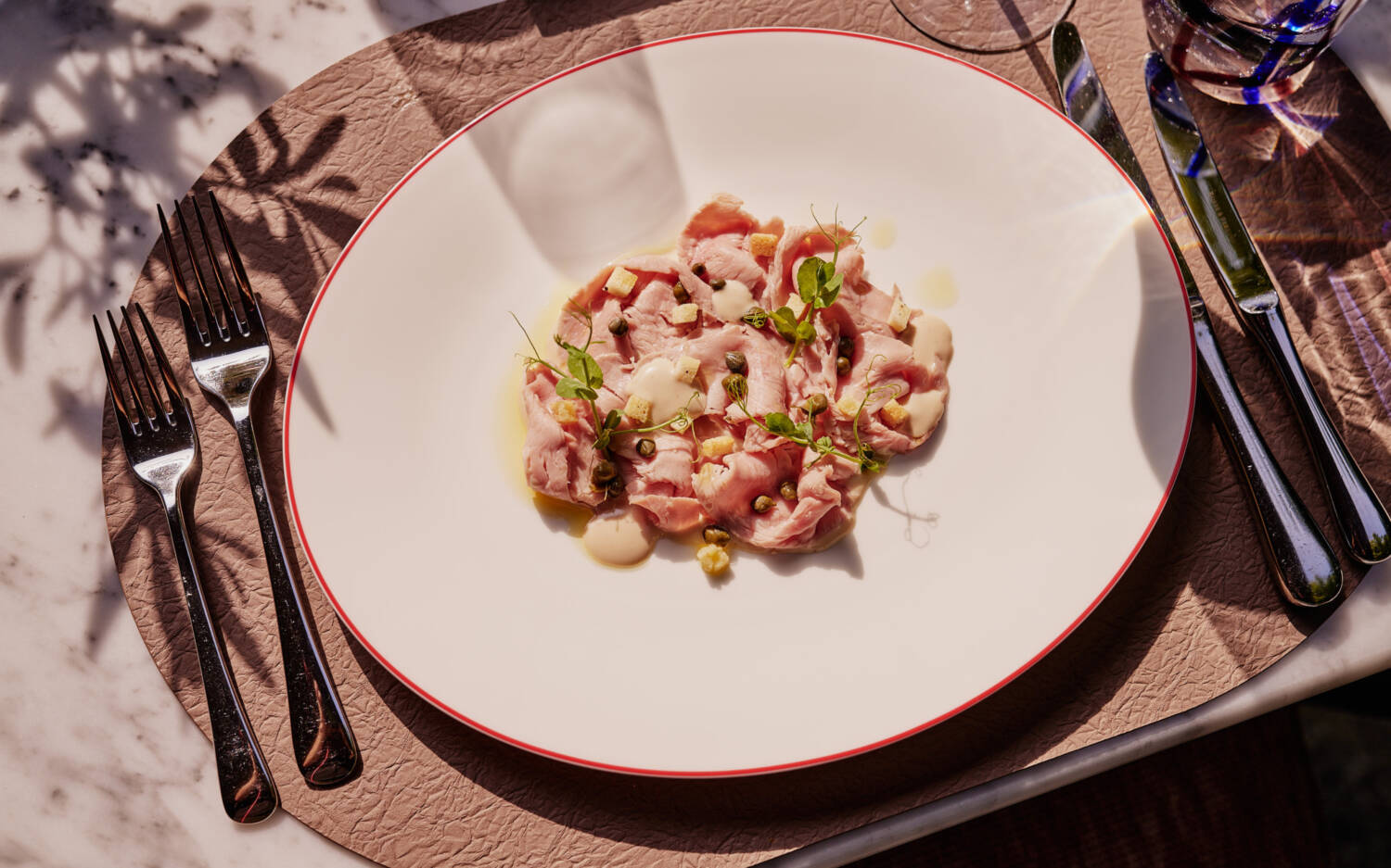 Hauchdünnes, zartes Fleisch, dazu ein charmantes Sößchen und Kapern sowie Croutons. Das Ganze muss natürlich mit feinen Kräutern garniert werden, um das Bildnis sowohl als auch den Geschmack zu vollenden / ©The Fontenay