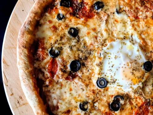 Knuspriger Rand, ordentlich Käse und ein Ei mittendrin machen diese Pizza zum echten Hingucker / ©Unsplash/Masimo Grabar