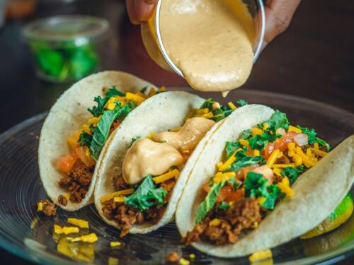 Taco-Trio mit ordentlich Wumms! Würzige Füllung und cremige Soße machen jeden Bissen schön saftig / © Unsplash/Jarett Lopez